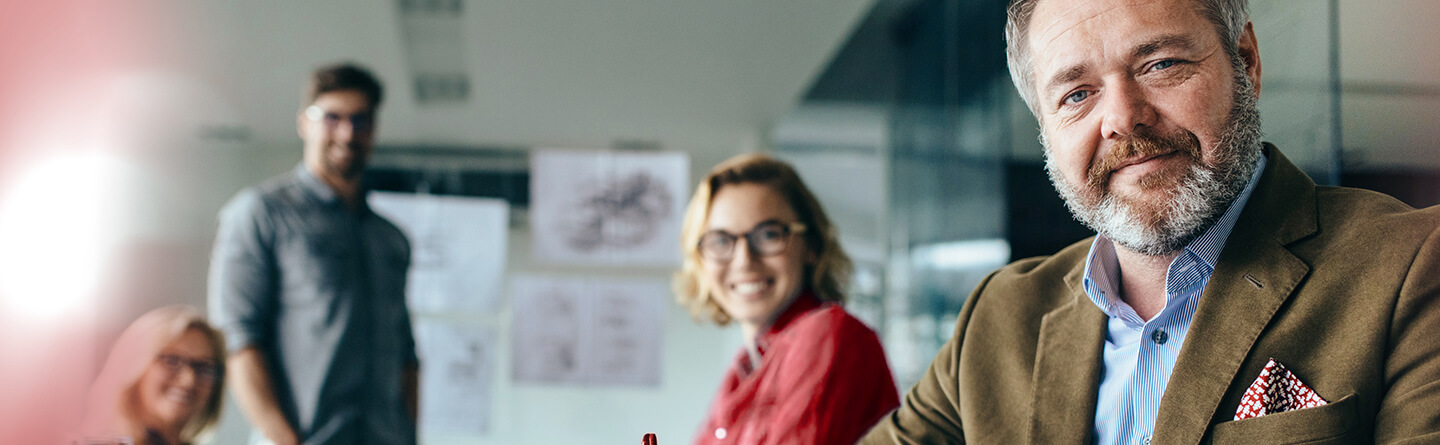 Ein lächelnder Mann und eine lächelnde Frau sitzen in einem Seminar für Betriebsräte. 