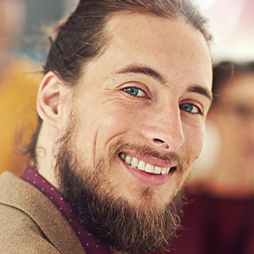 Ein junger Mann mit Bart lacht 