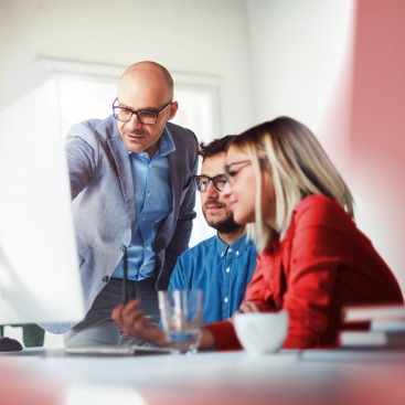 2 Männer und eine Frau vor einem PC