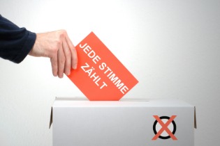 Ein Mann wirft einen Wahlzettel in eine Box